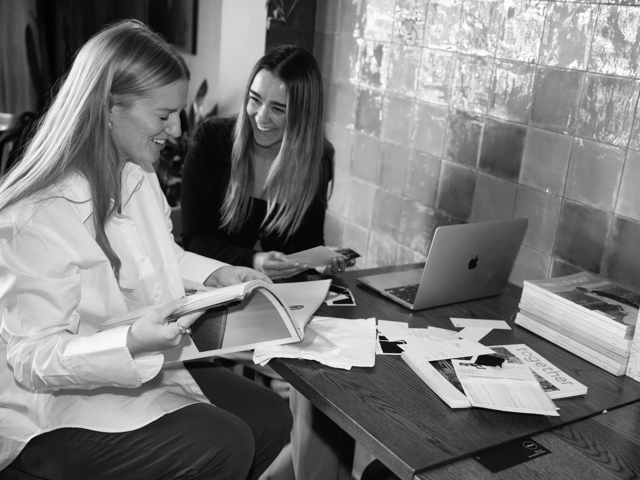 Soirée planners reviewing design samples and wedding ideas at a laptop, in black and white.