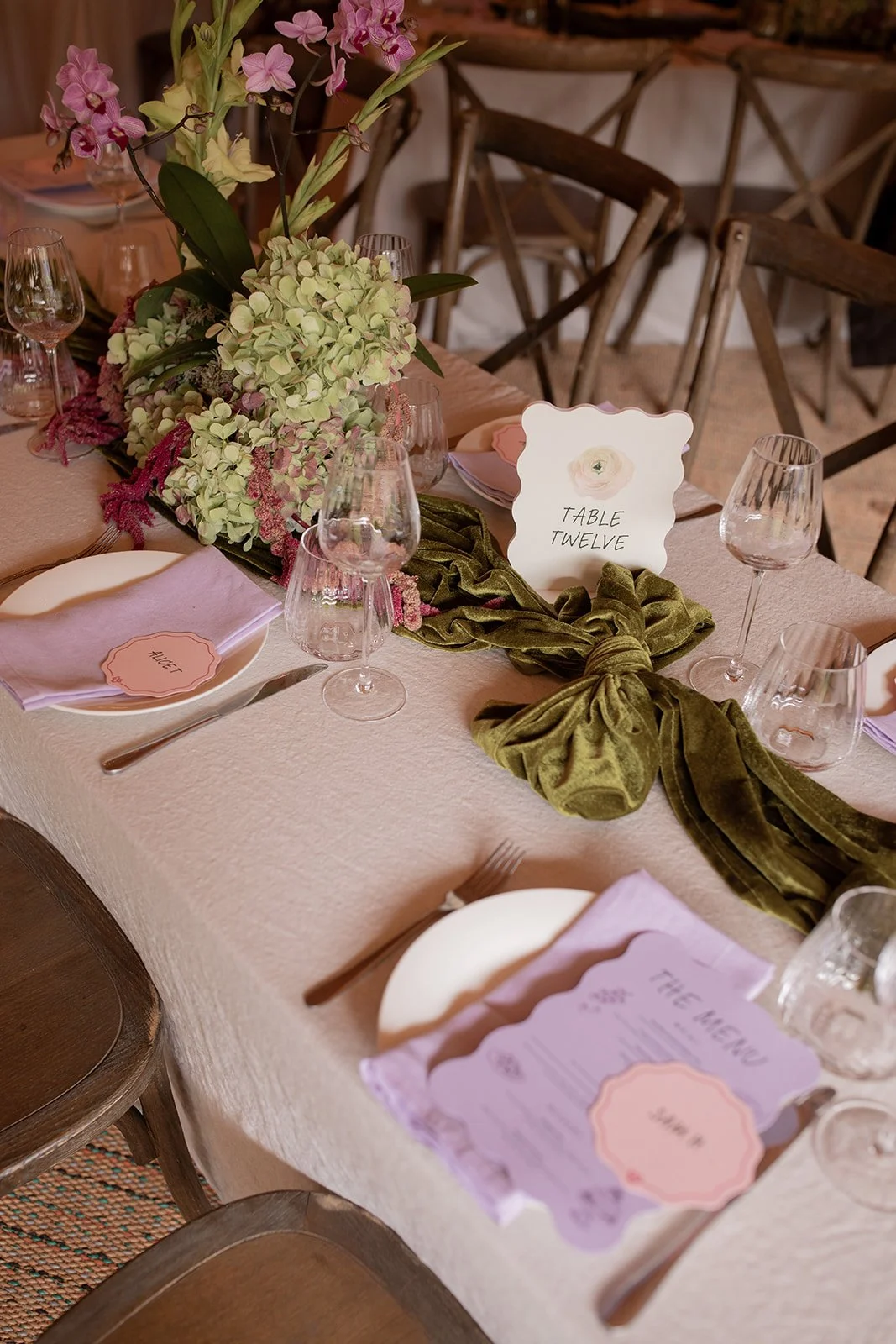 Wedding table with pink stationery, green velvet bows and pastel flowers.