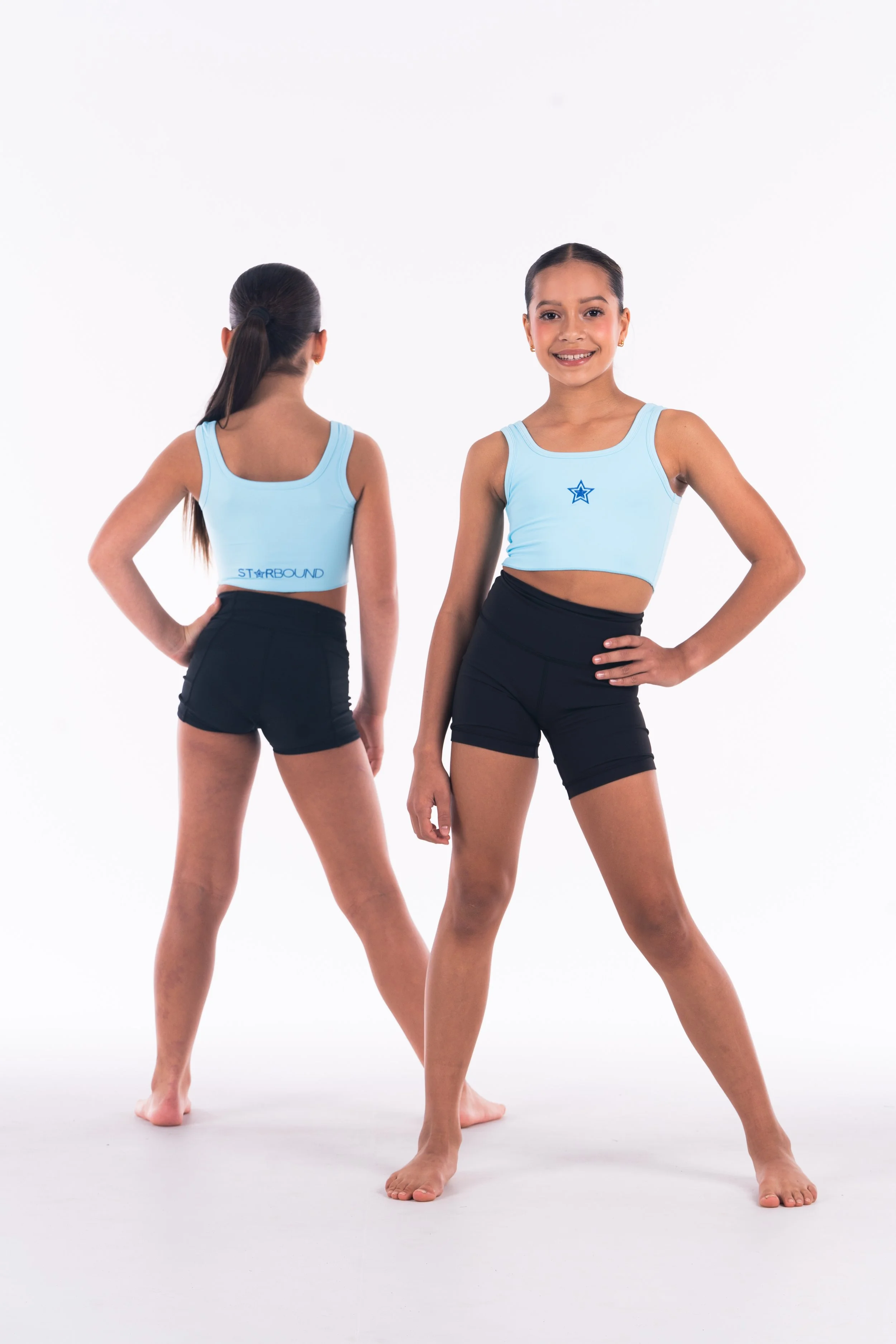 Two young dancers in matching blue Starbound tops and black shorts posing for a promotional photo against a white background.