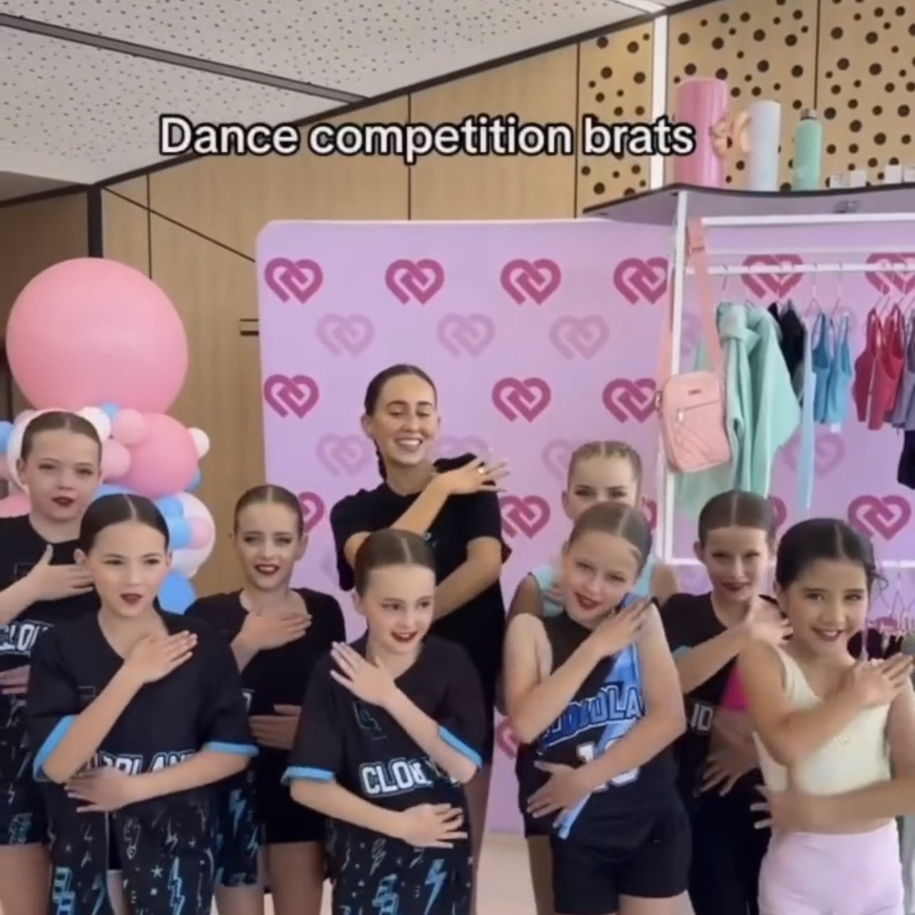 Starbound dance group of young girls and instructor posing with hands over hearts at the Claudia Dean World pop-up stall.