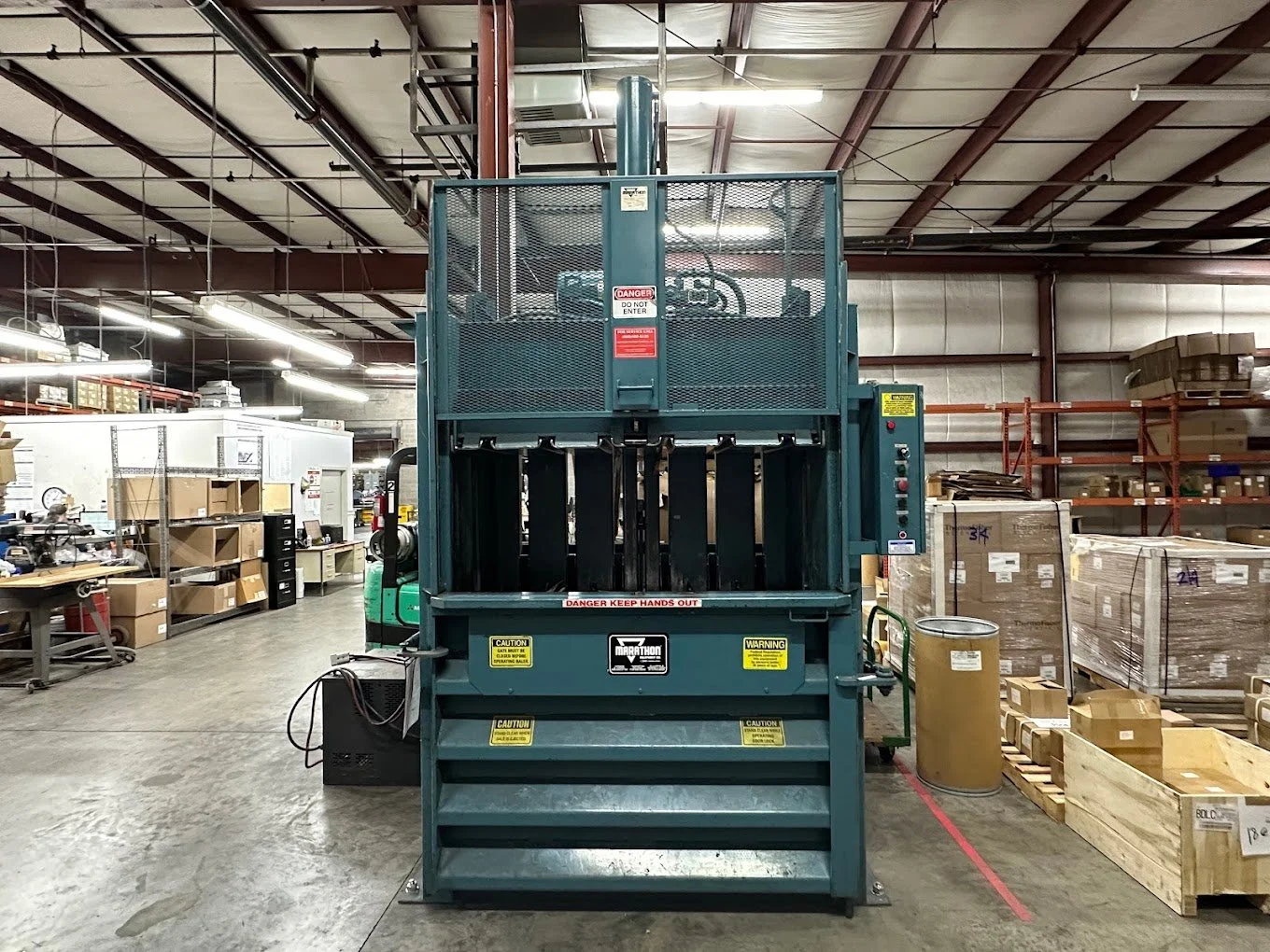 Industrial hydraulic lift with black forks, set in a warehouse with shelves and boxes.