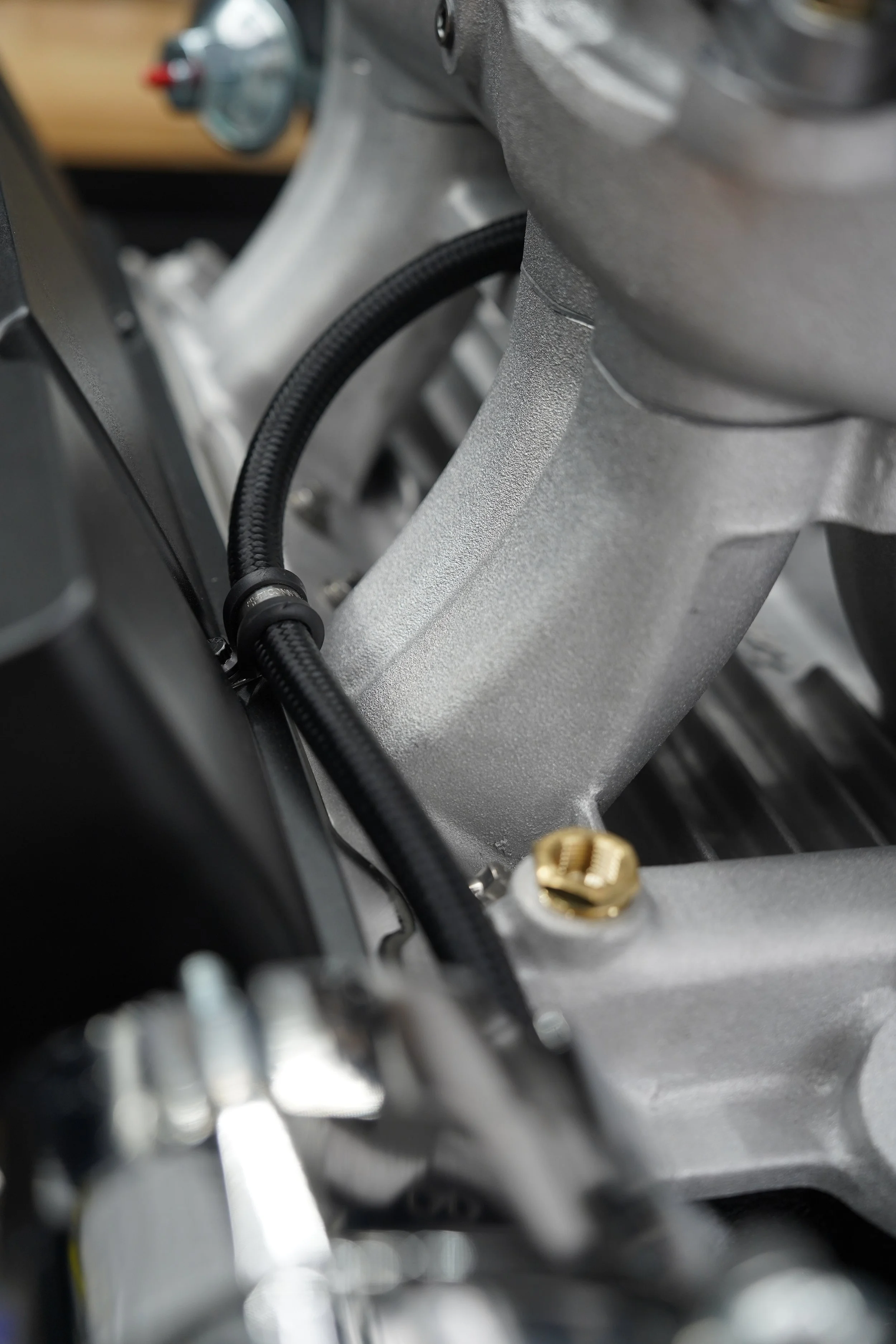 Close-up of a metallic engine component with a black cable and a brass screw.