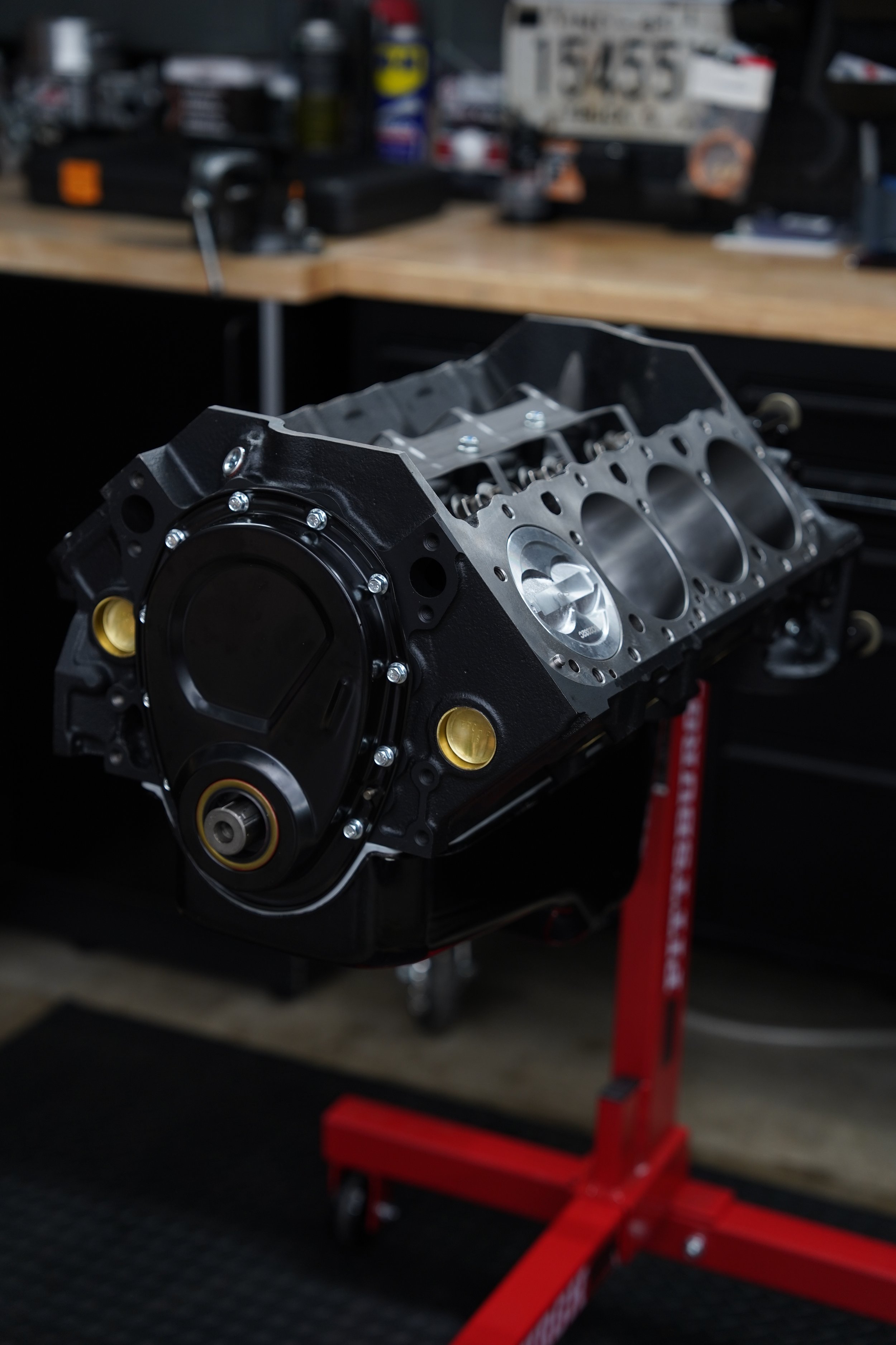 Close-up of a new engine block mounted on a stand in a workshop, with tools and supplies in the background.