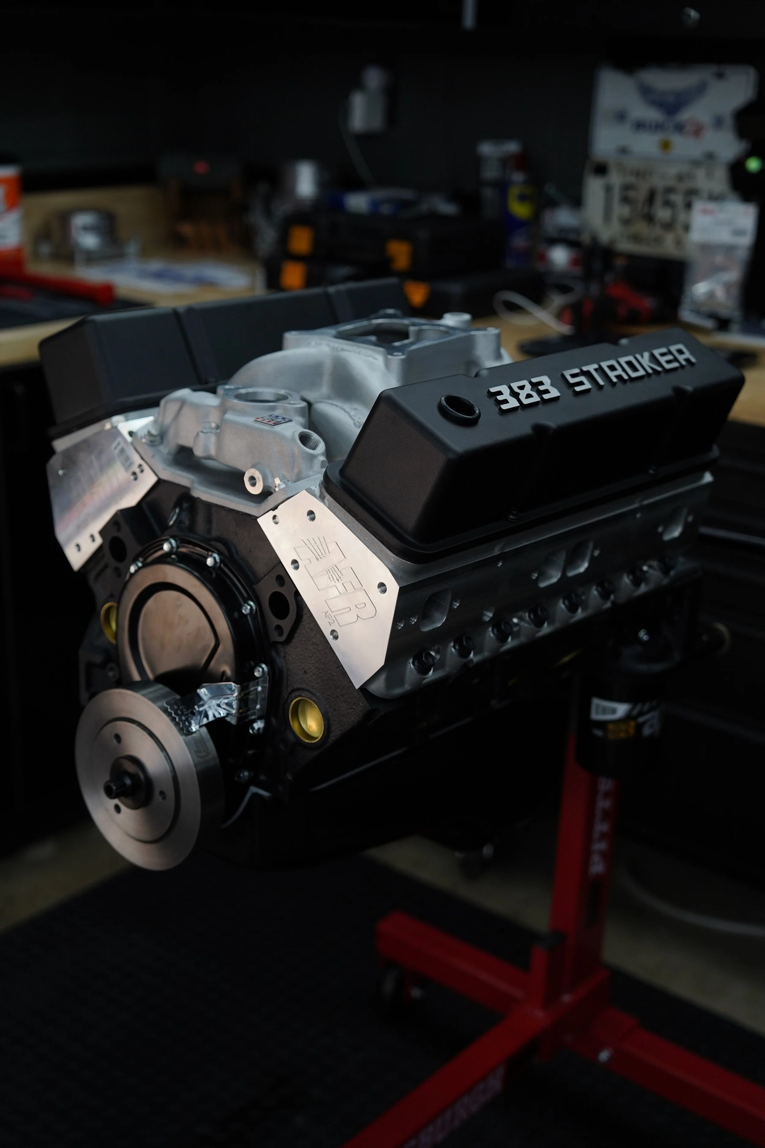 Race car engine with the label '382 STROKER' mounted on a workbench in a workshop.