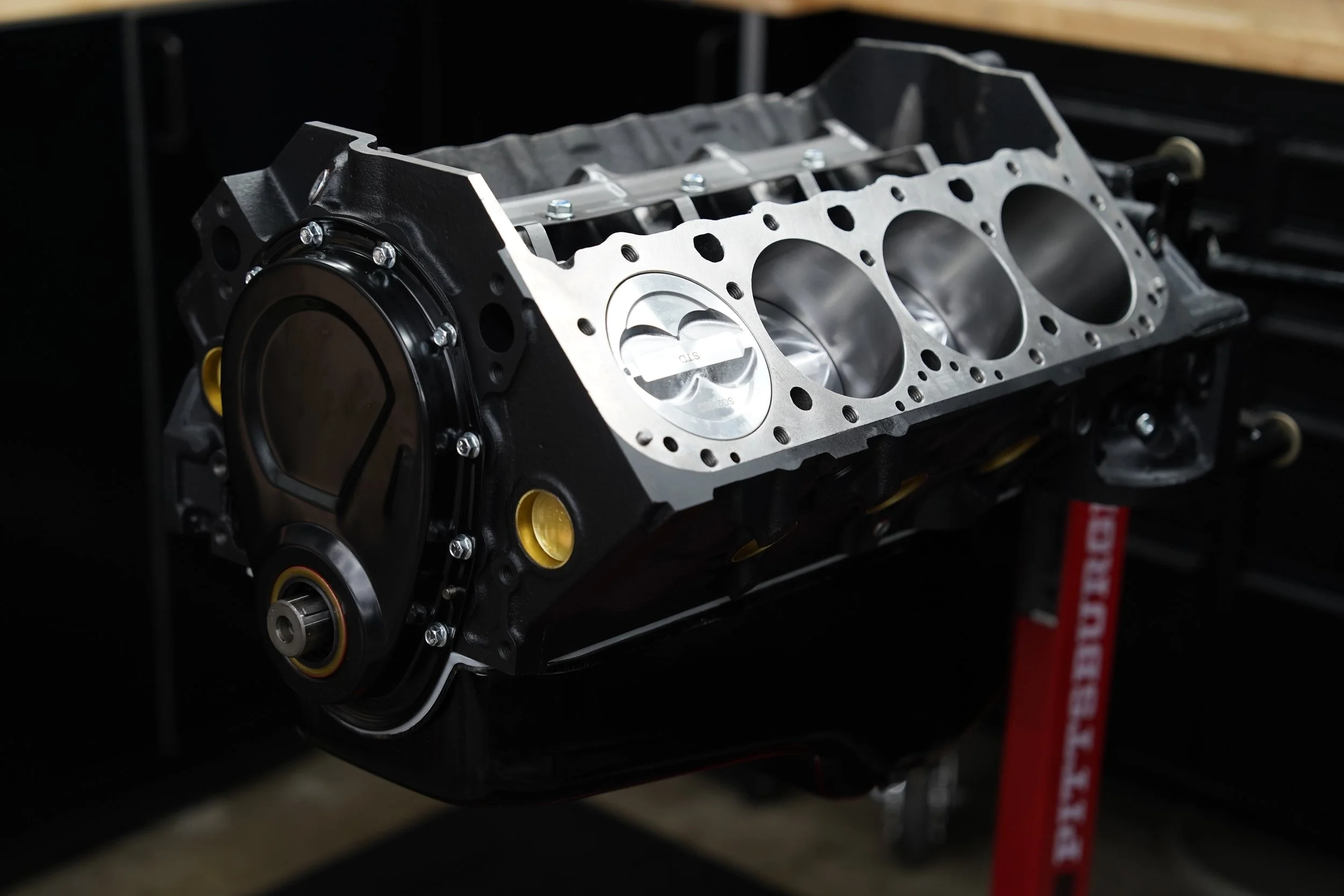 Close-up of a car engine block on a stand in a workshop setting.