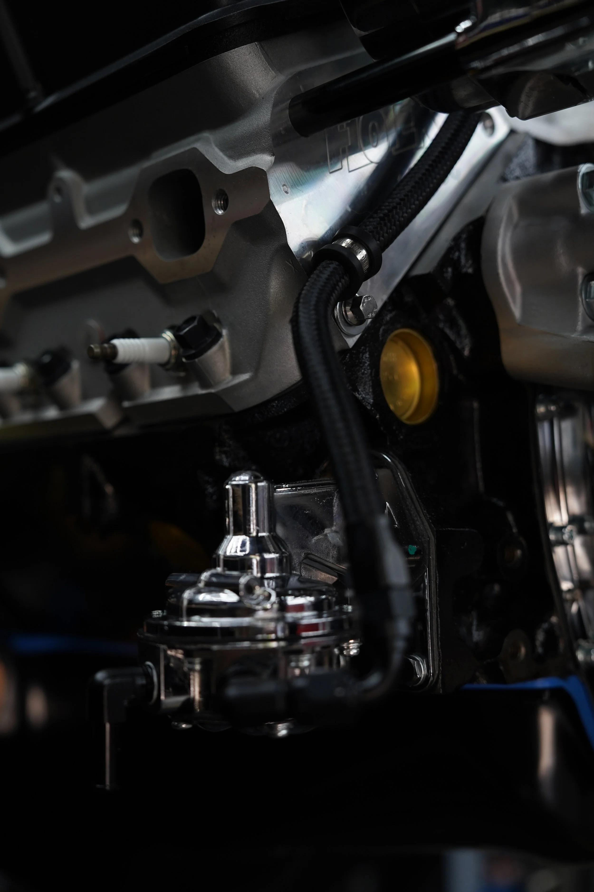 Close-up of a car engine, showing metallic engine components and a black braided hose.