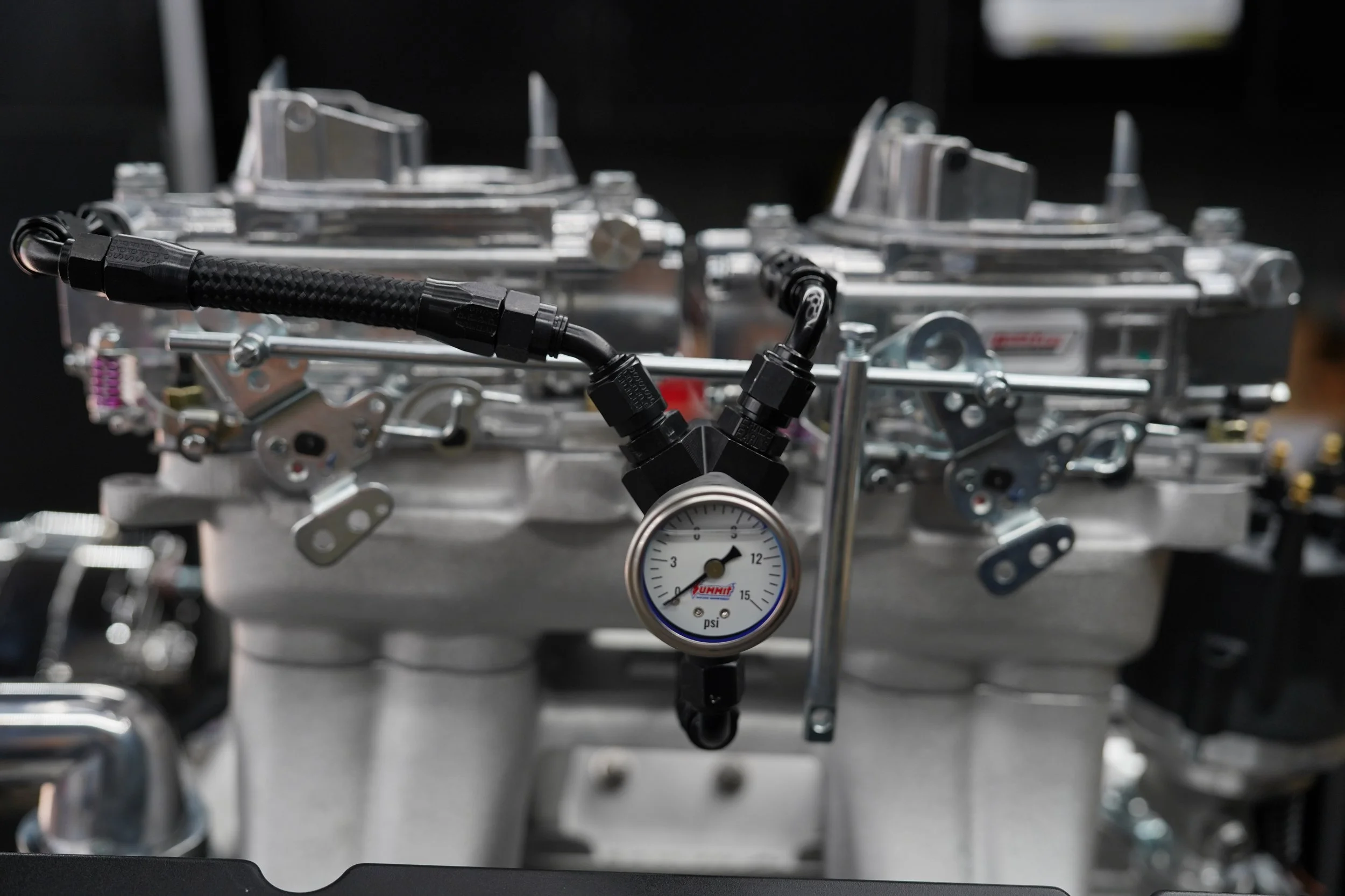 Close-up of a mechanical device with metal components, hoses, and a gauge showing pressure in PSI.