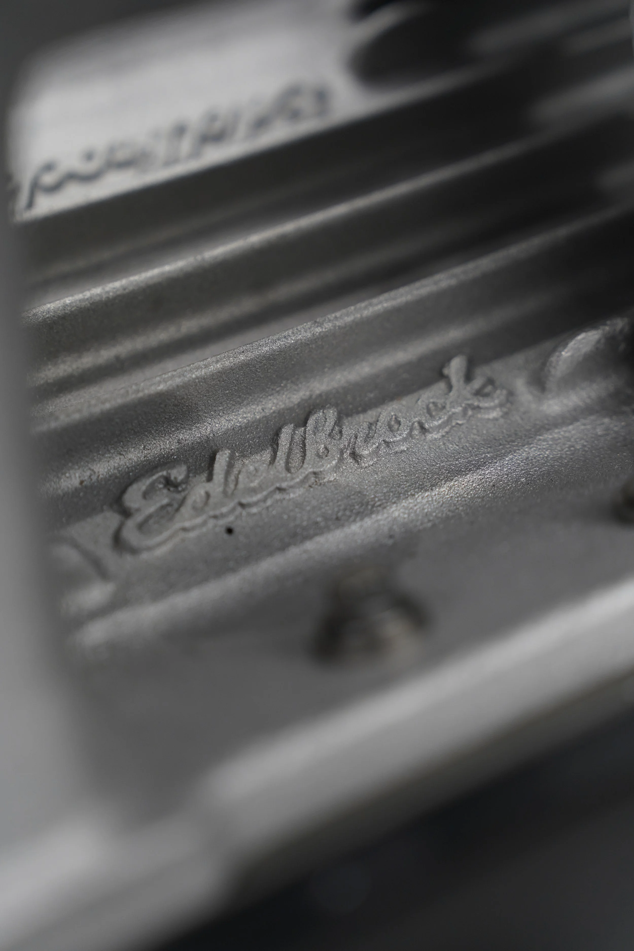 Close-up of a metallic object with engraved cursive writing, showing the word 'Slick' and part of another word underneath.