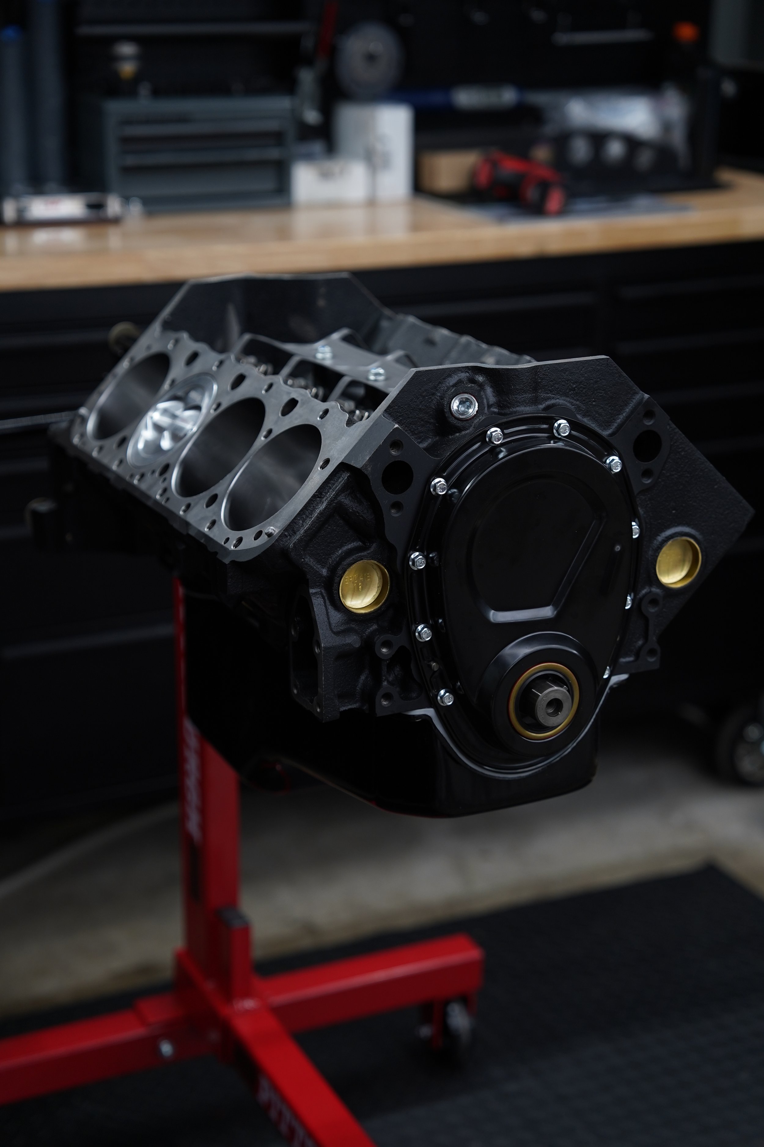 A car engine block mounted on a red engine stand in a workshop.