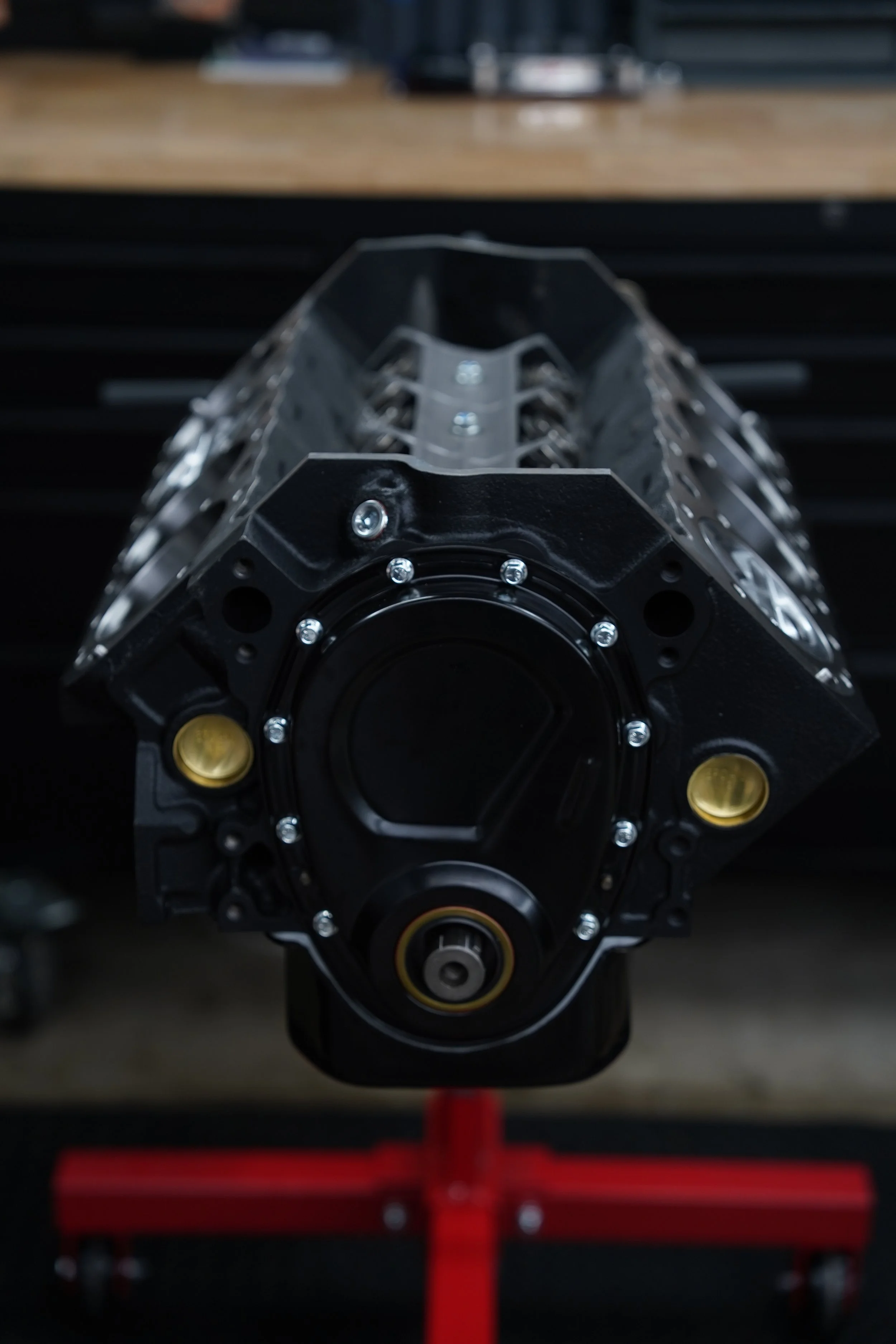 Close-up of a car engine block mounted on a stand in a workshop.