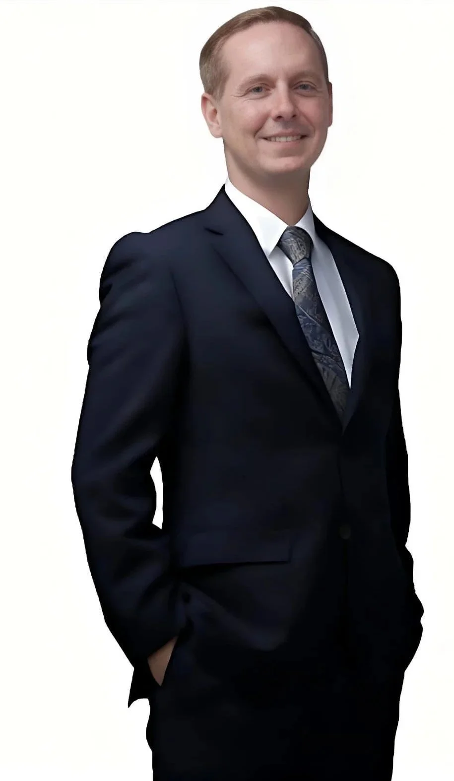 Evan Shoemaker smiling, wearing a suit, hands in pockets