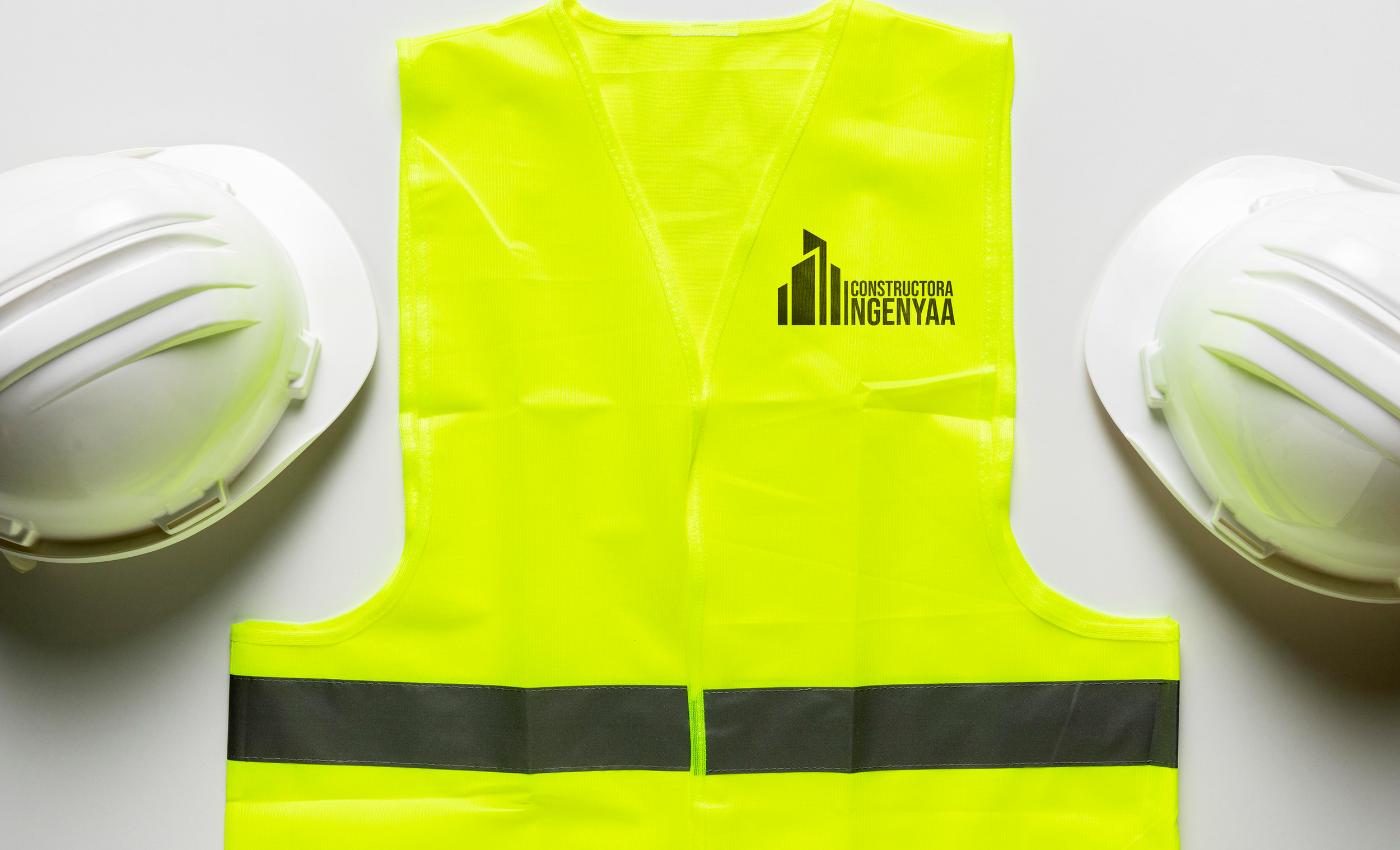 Chaleco de seguridad con el logotipo de INGENYAA y cascos de construcción, representando la identidad visual y el profesionalismo de la empresa en obra.