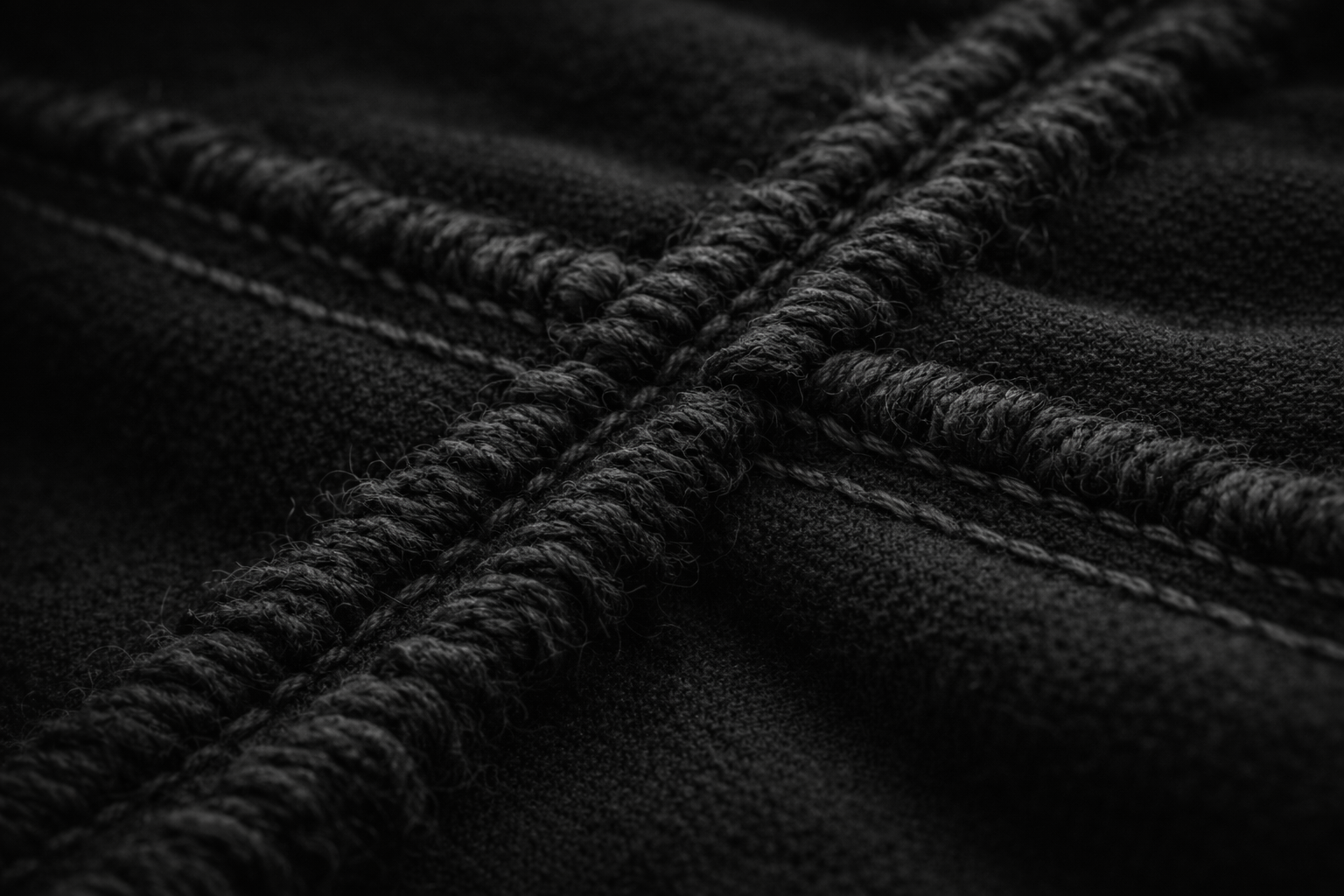 Close-up of black fabric with detailed stitching and thick black cords.