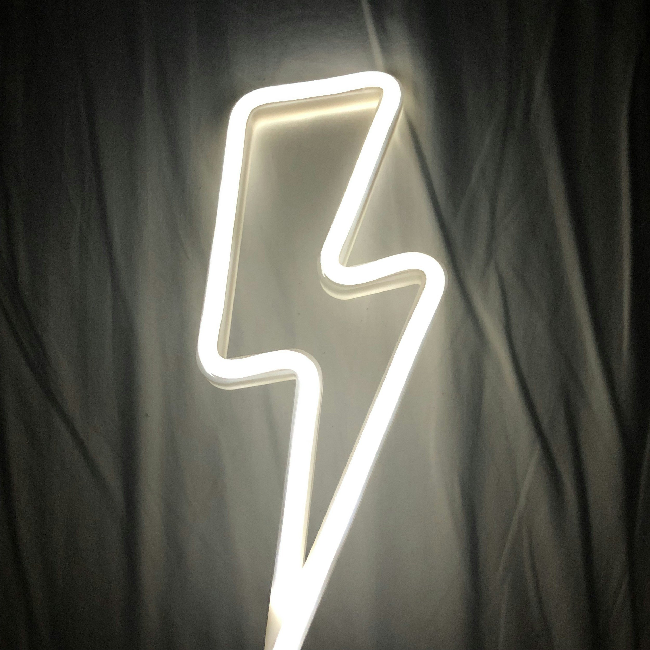 Neon sign of a lightning bolt against a dark background.