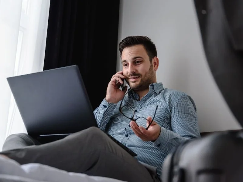 man on the phone looking at laptop in his lap