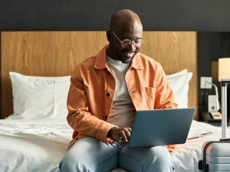 man sitting on bed with laptop in his lap