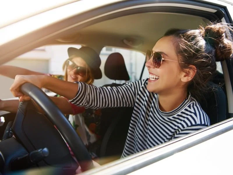 two women smiling in car with windows down