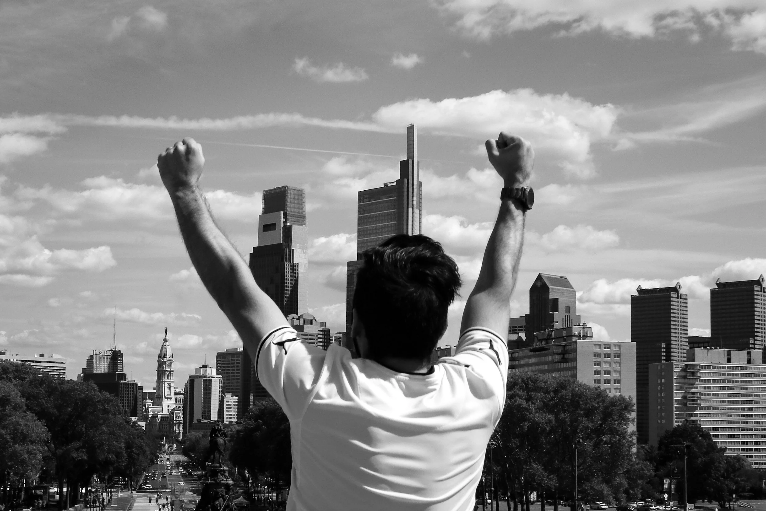 A person with raised fists in front of a city skyline with skyscrapers.