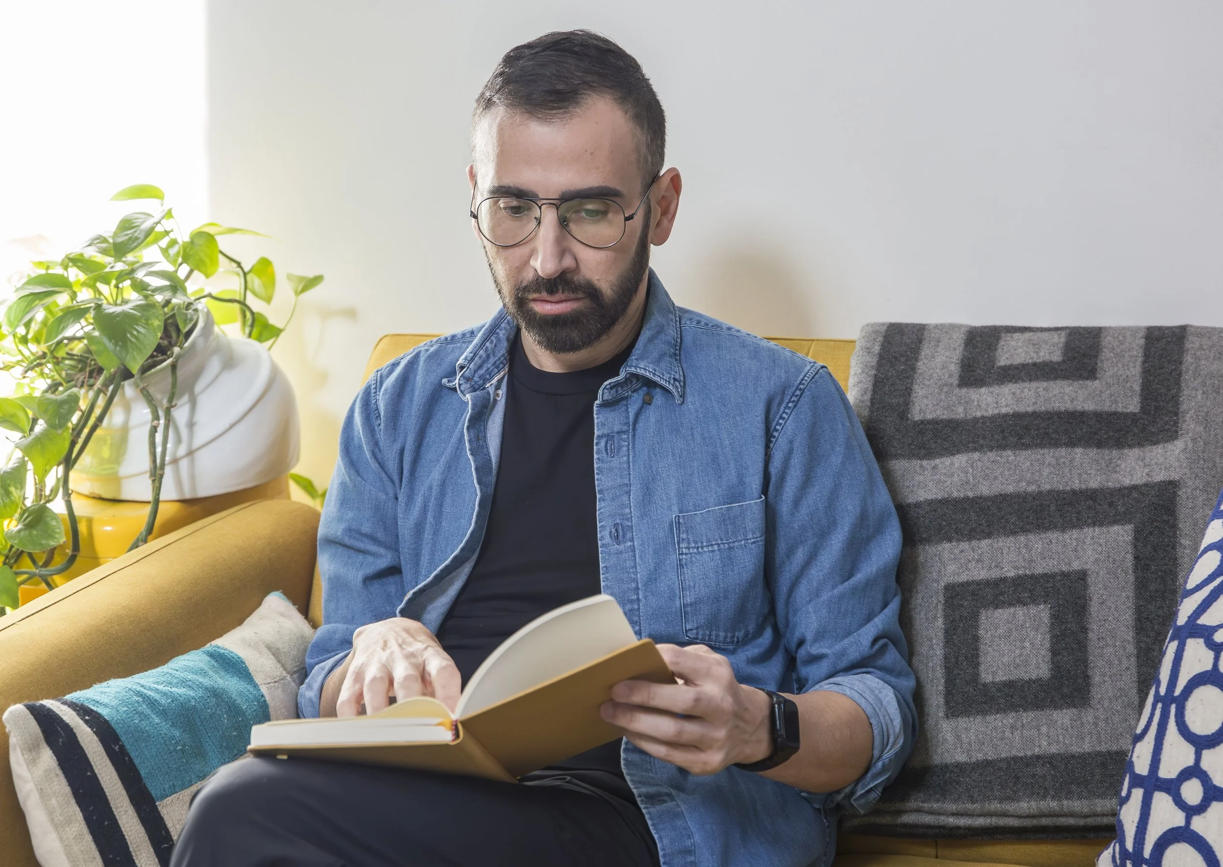 Alex Barragan, gay men's therapist, reading a book in a warm therapy space