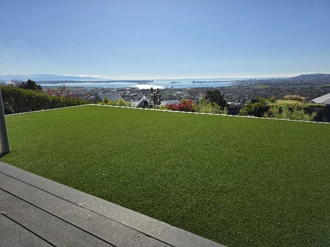 View from a patio overlooking a cityscape and a large body of water under a clear blue sky.