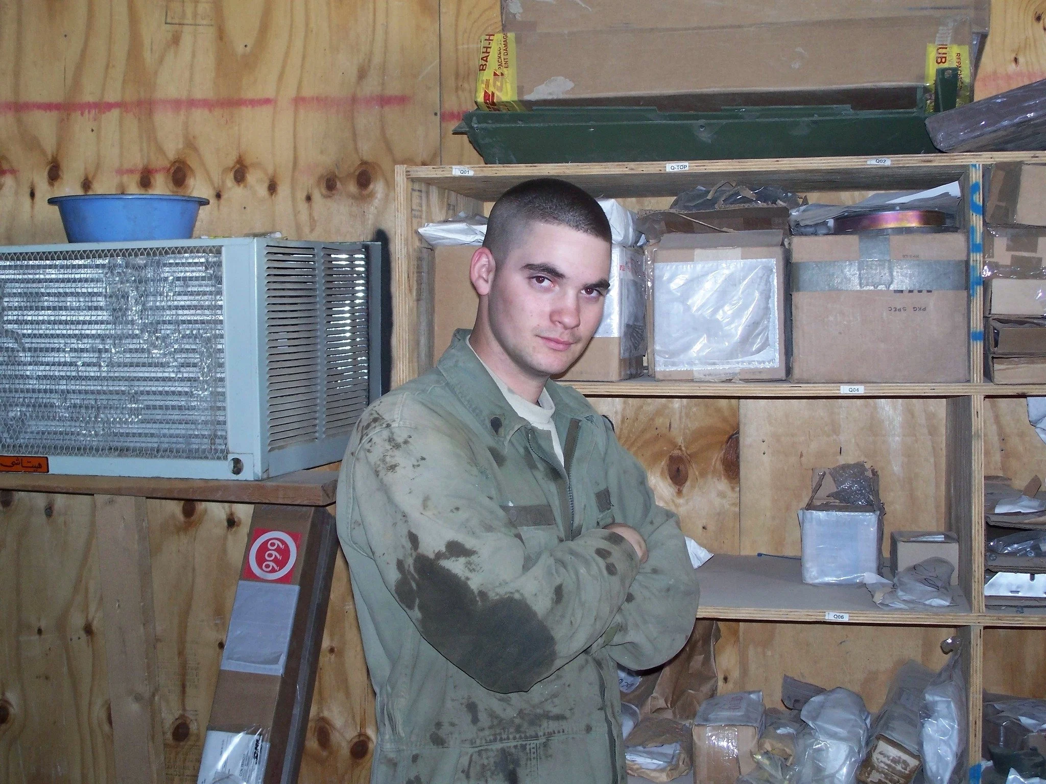 A man in a military uniform standing in front of shelves filled with boxes and packages in a storage room.