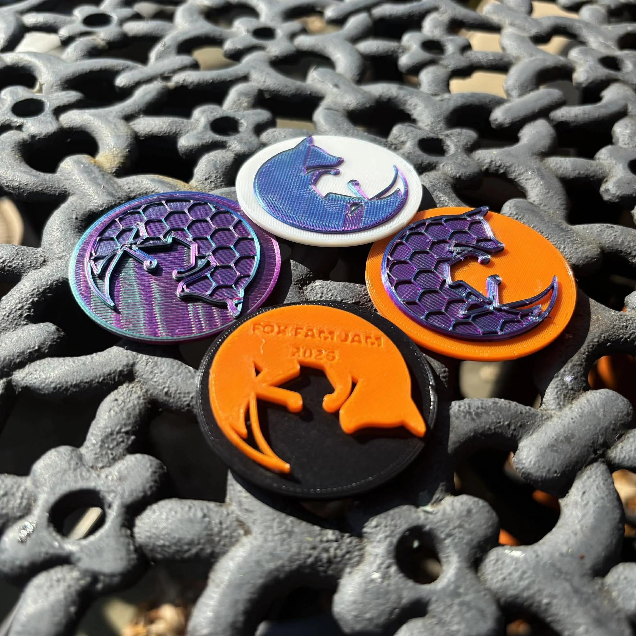 Four round tokens with dragons and honeycomb patterns on a metal surface with a grid pattern.