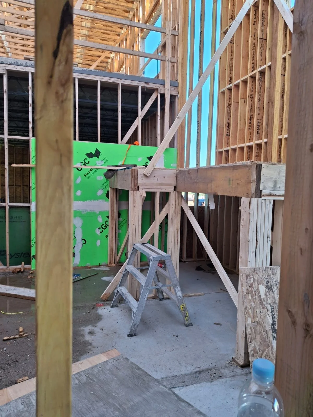 Construction site with wooden framing, a small wooden staircase, a stepladder, and building materials.