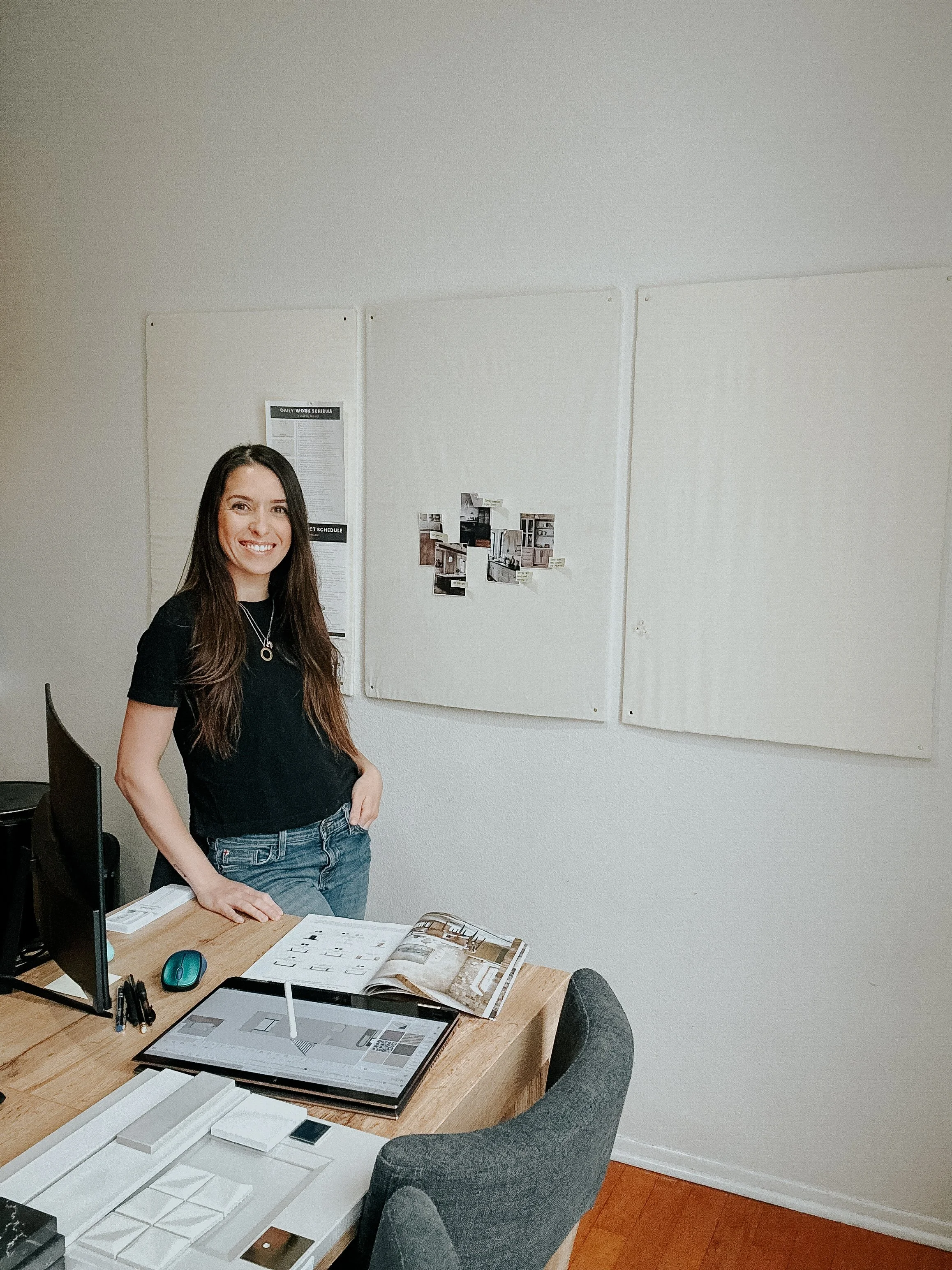 A wedding cake with a bride and groom topper, surrounded by flowers on a table with wine glasses, plates, and a calendar.