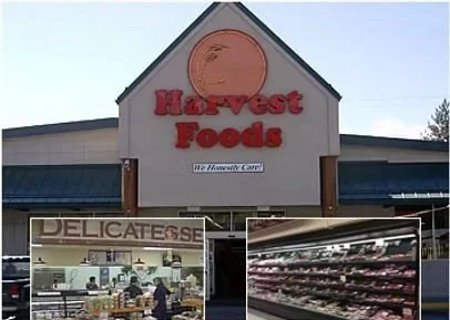 Exterior view of Harvest Foods grocery store with produce and deli sections visible.