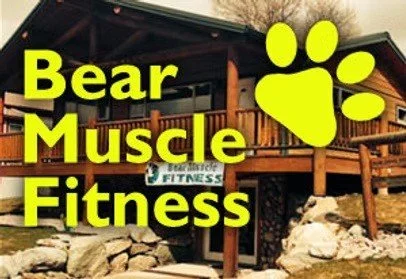 Signboard with the text 'Bear Muscle Fitness' and a large yellow paw print logo outside a building.