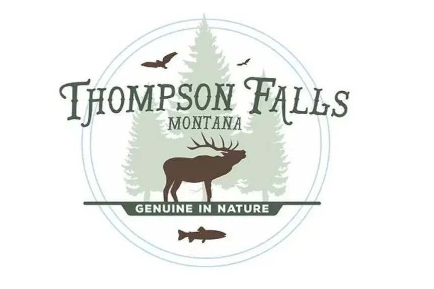 Logo for Thompson Falls, Montana, featuring a moose, trees, birds, and a fish with the text 'Genuine in Nature'.