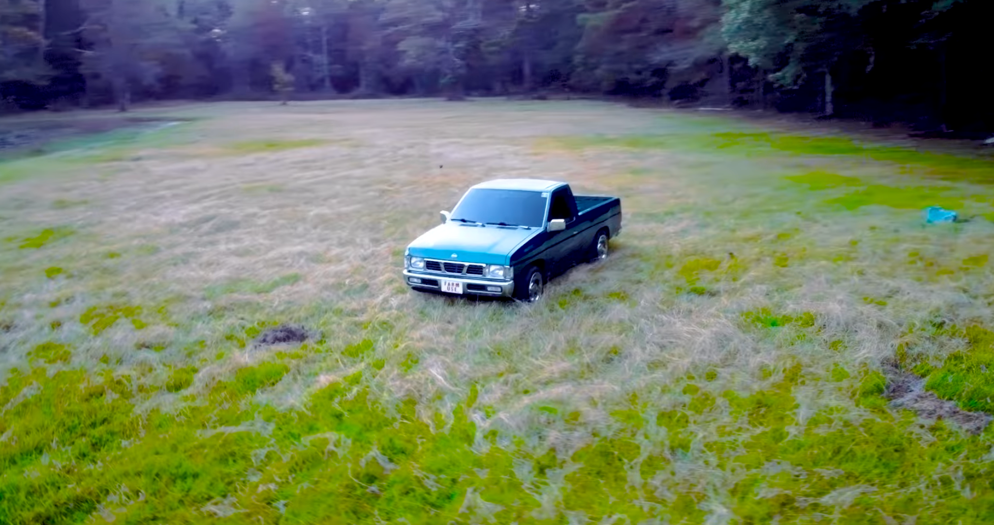 A black pickup truck parked on a grassy field with trees in the background.