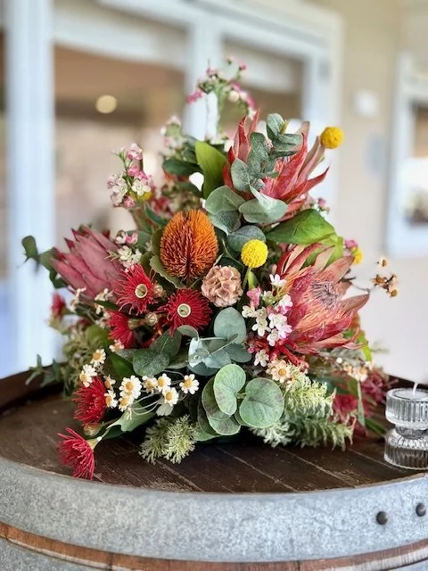 A colorful arrangement of dried flowers and greenery on a wooden surface.