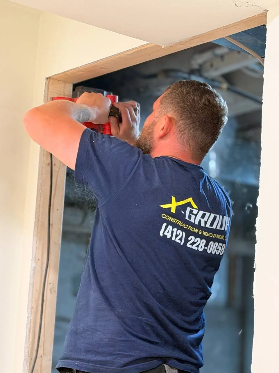 A man using a power drill to work on a doorway during home renovation.