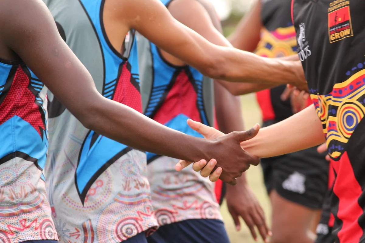 Two athletes in sports uniforms shaking hands during a sporting event.