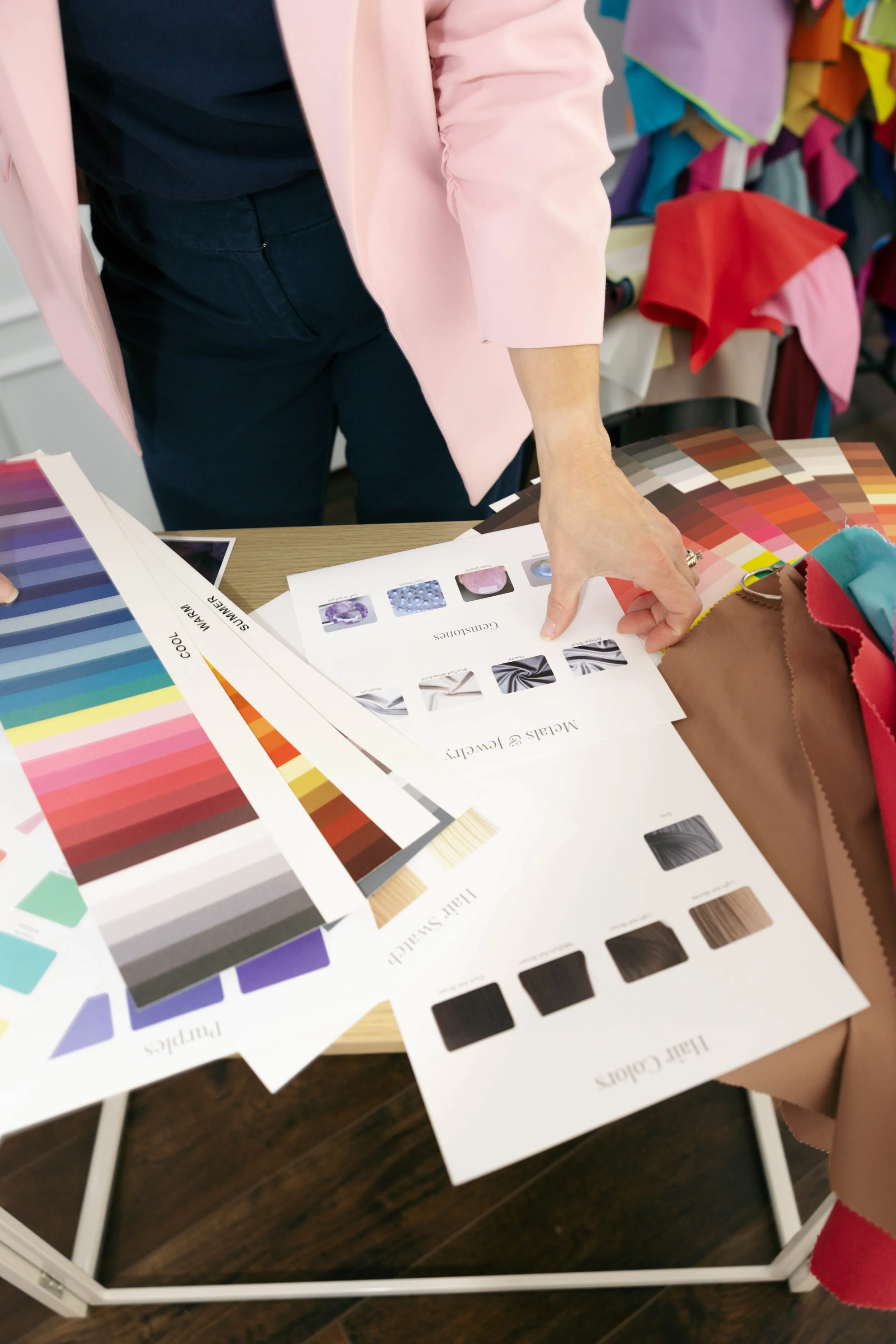 Color swatch books and fabric samples on a table, with a person pointing at one of the cards.