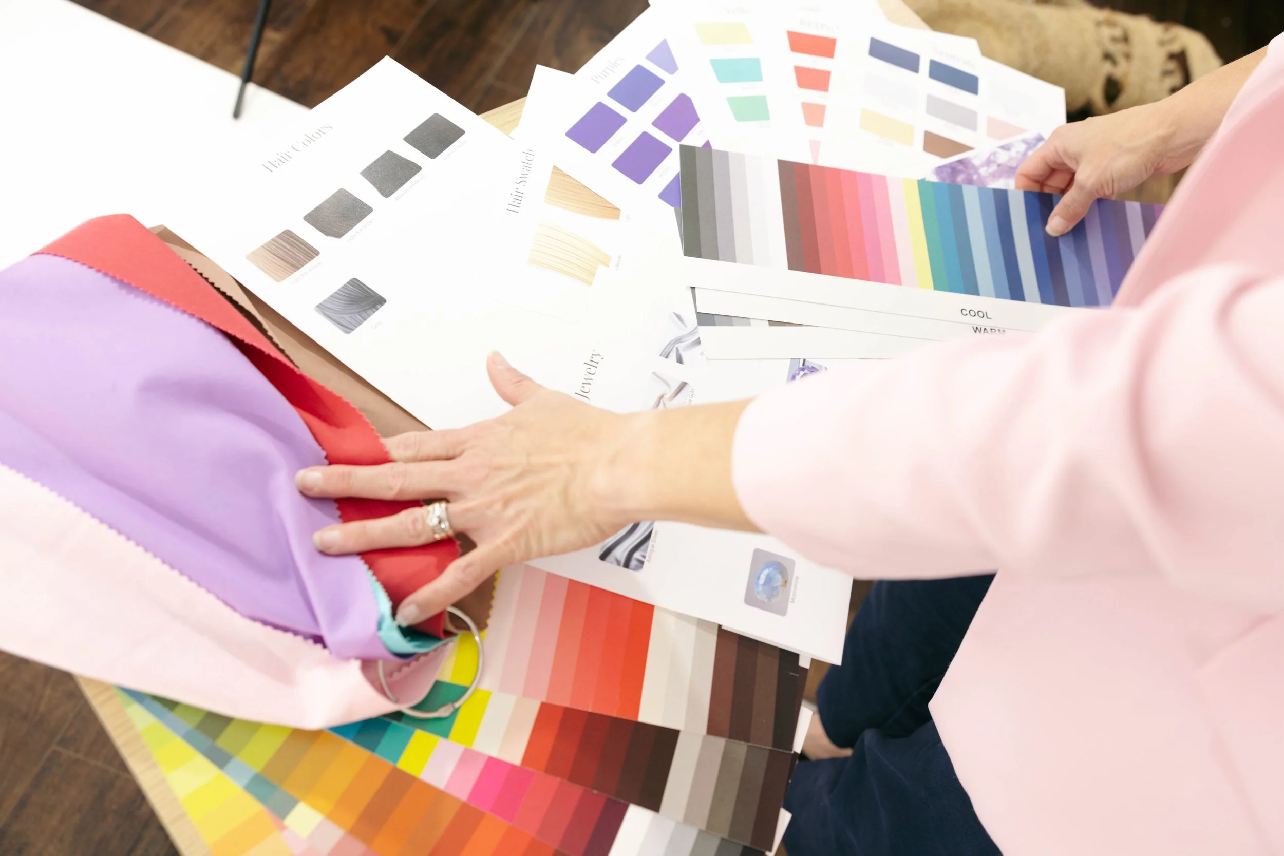 Person holding a color palette while looking at various swatches of color and fabric samples on a table.
