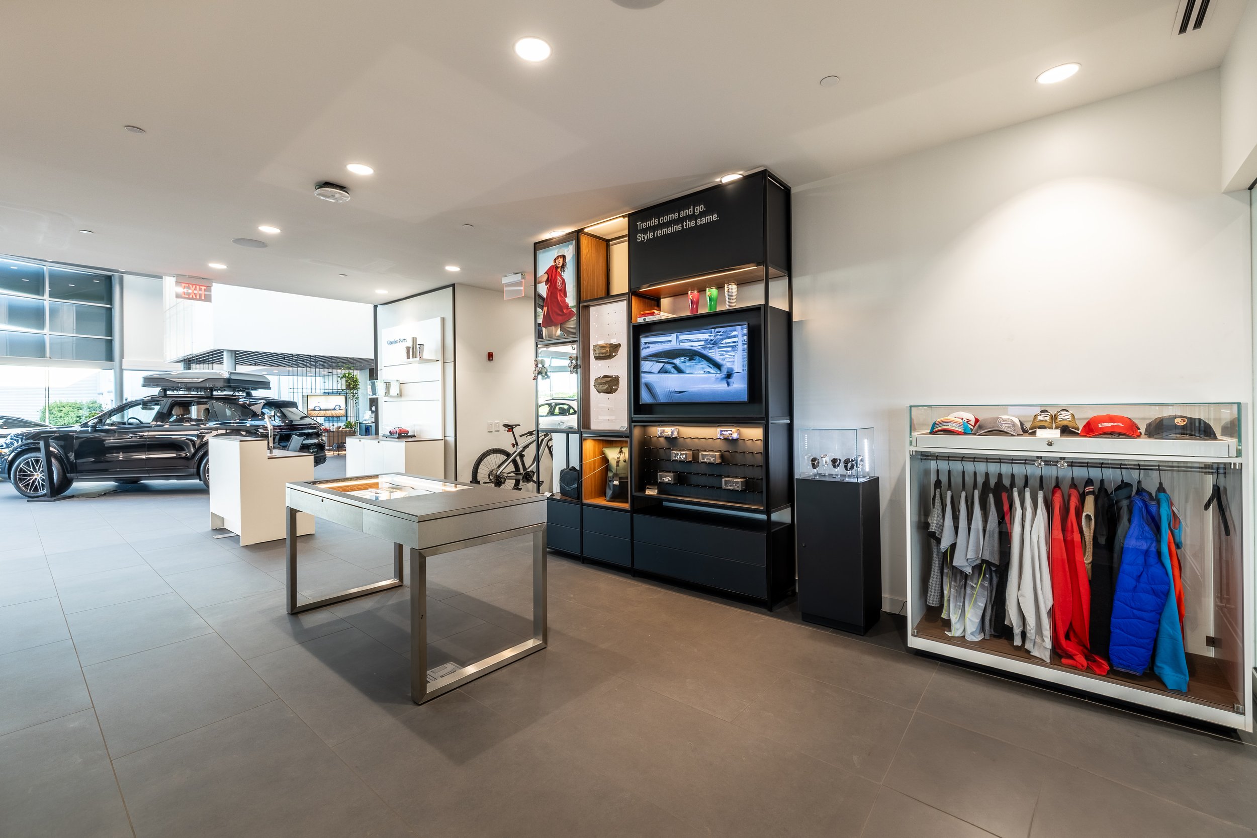 Car dealership showroom with a black luxury SUV and various merchandise like hats, clothing, and accessories displayed.
