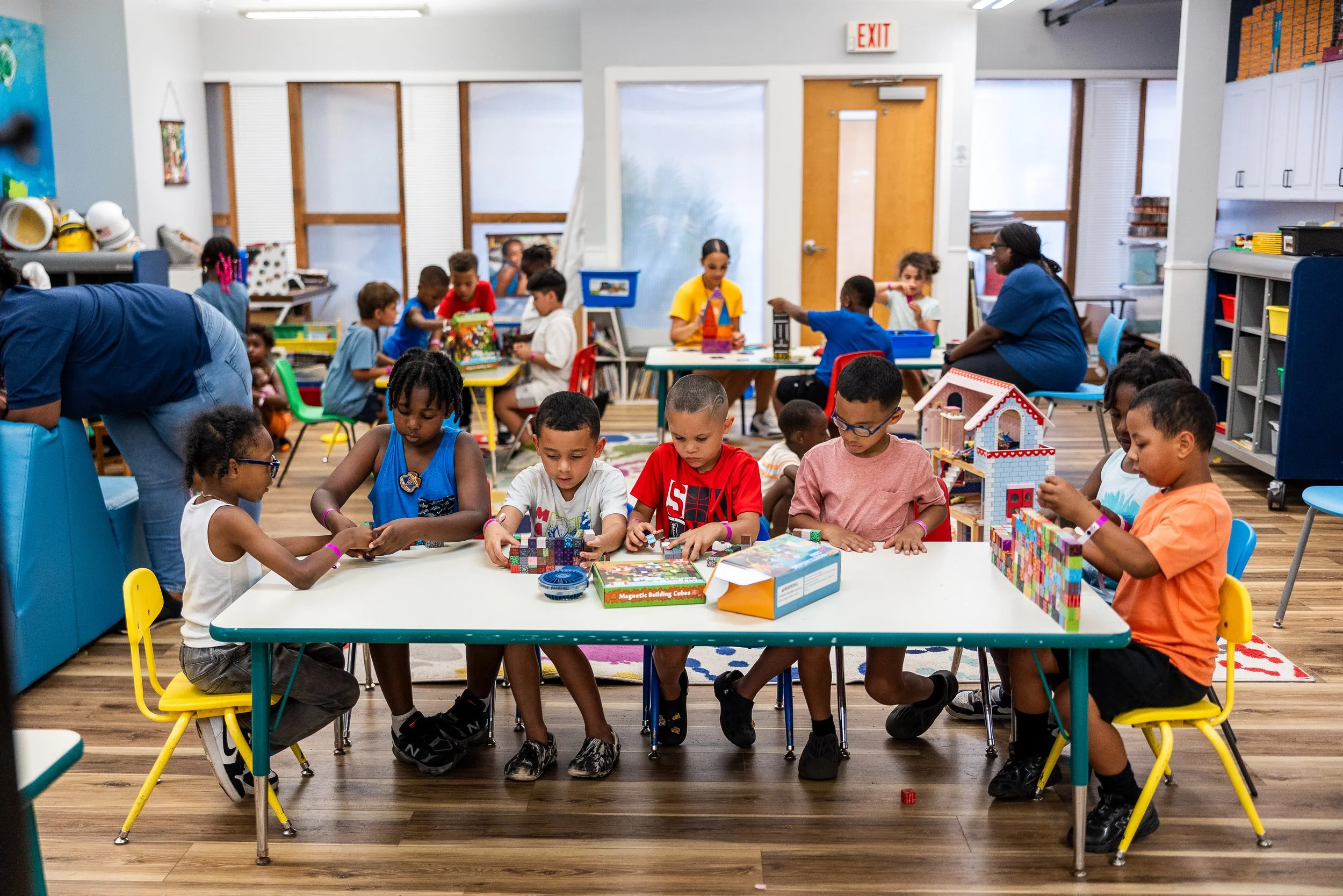 Children sitting at tables playing with toys in a classroom.