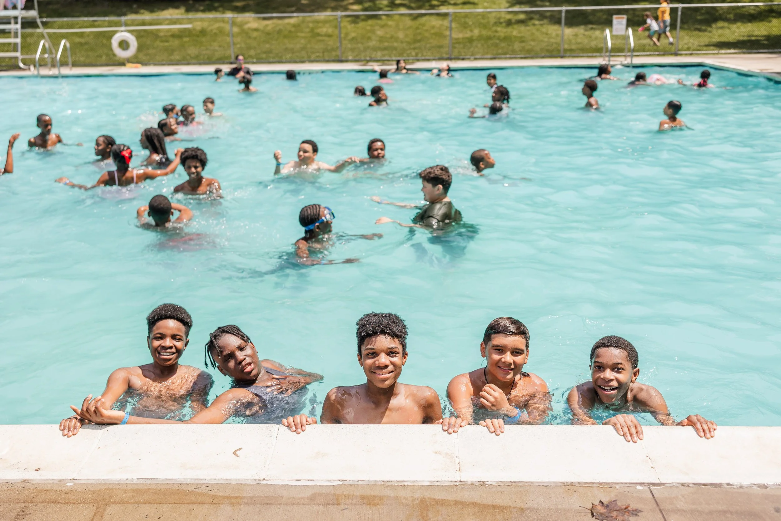 Children swimming and enjoying in a large outdoor swimming pool during daytime.
