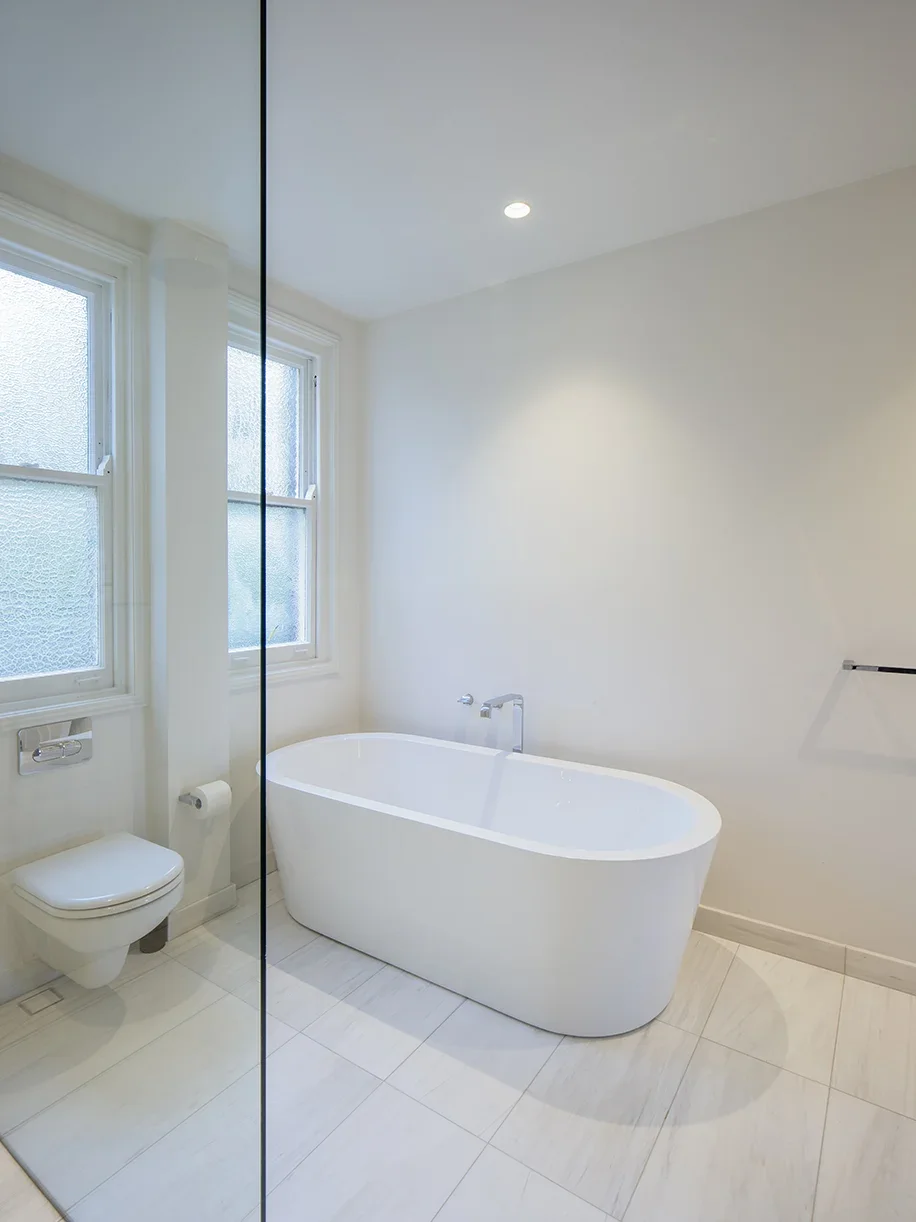 Modern bathroom with white bathtub, toilet, and large windows with frosted glass, minimalist design, bright and clean