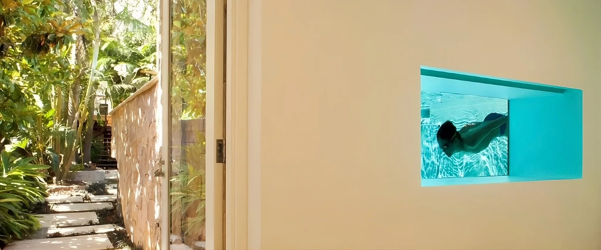 Swimming pool window view with swimmer framed by interior wall, overlooking tropical garden walkway at Bronte House by To The Mil.