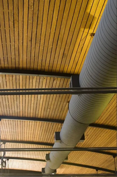 Ceiling with wooden panels, black beams, and a large gray ventilation duct.