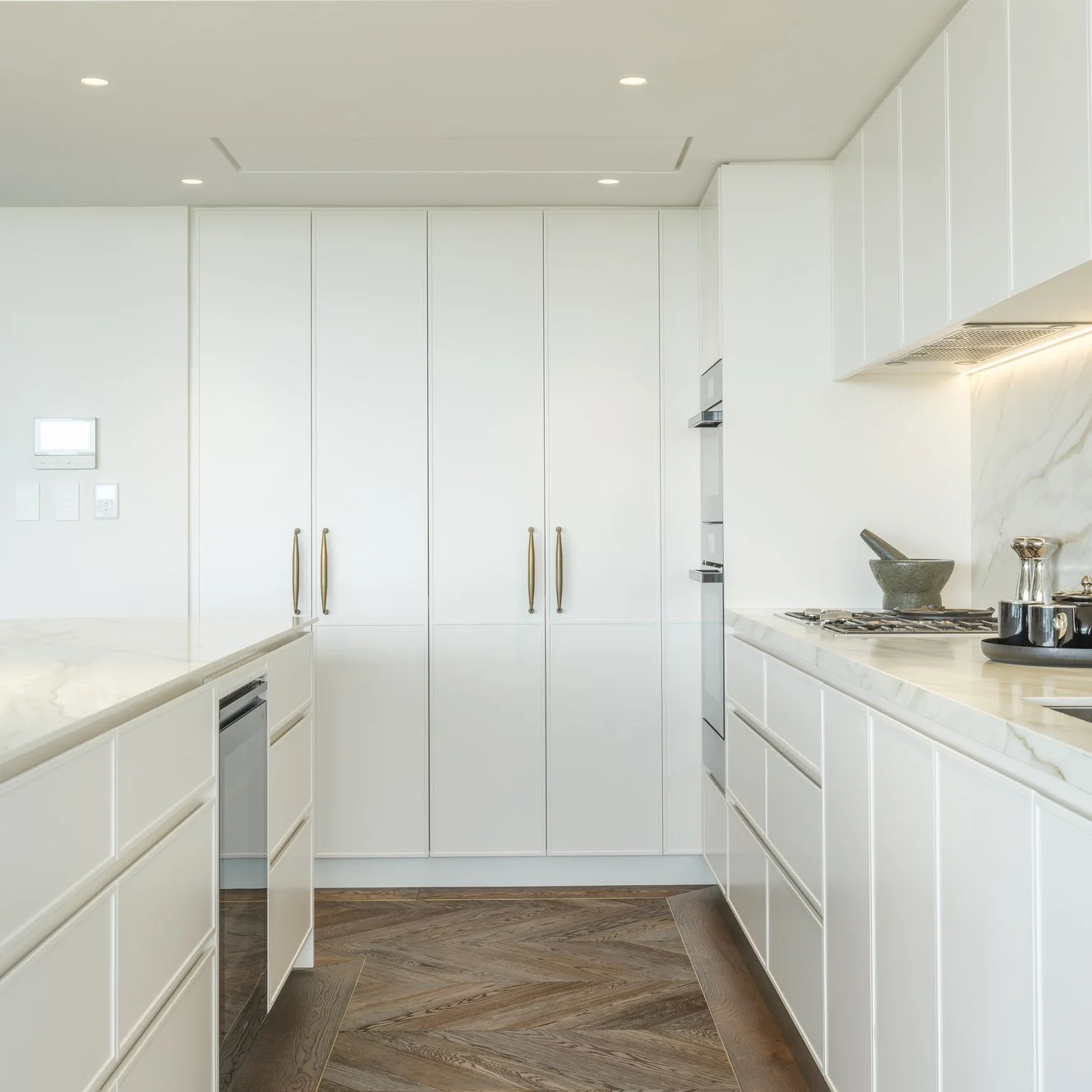 Potts Point Unit 2024 — high-end apartment renovation in Sydney featuring bespoke joinery, herringbone timber flooring with brass inlay, integrated lighting and a cohesive open-plan kitchen, living and dining space.