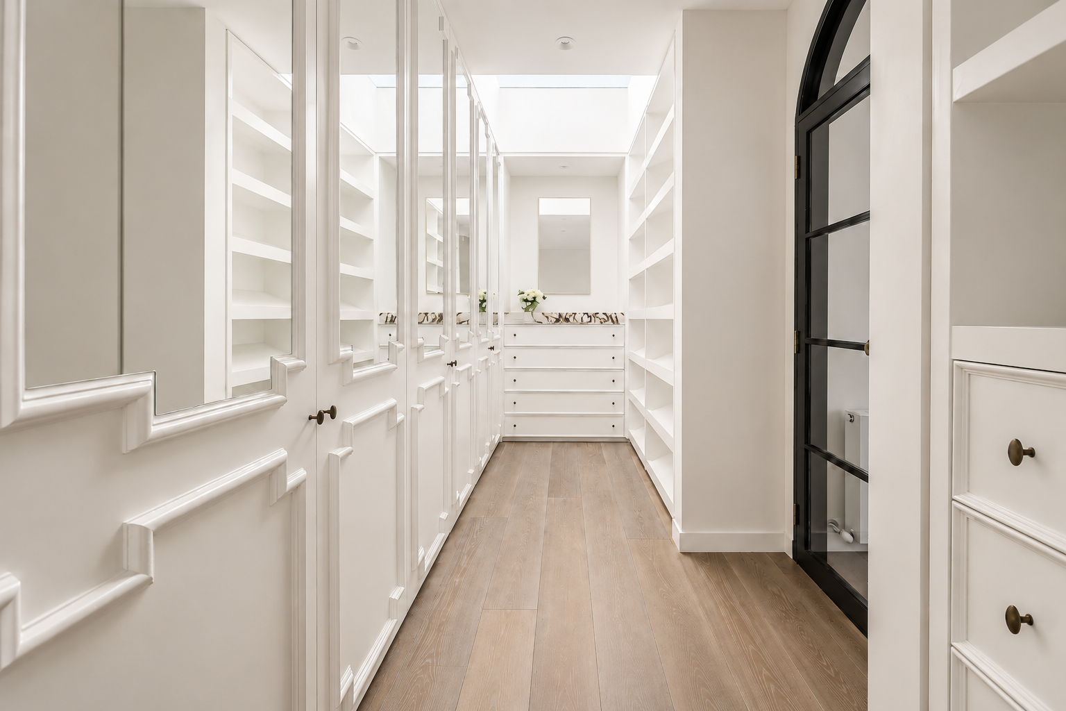 Custom walk-in wardrobe at Vaucluse House with mirrored cabinetry, white joinery, timber flooring and a skylight above.
