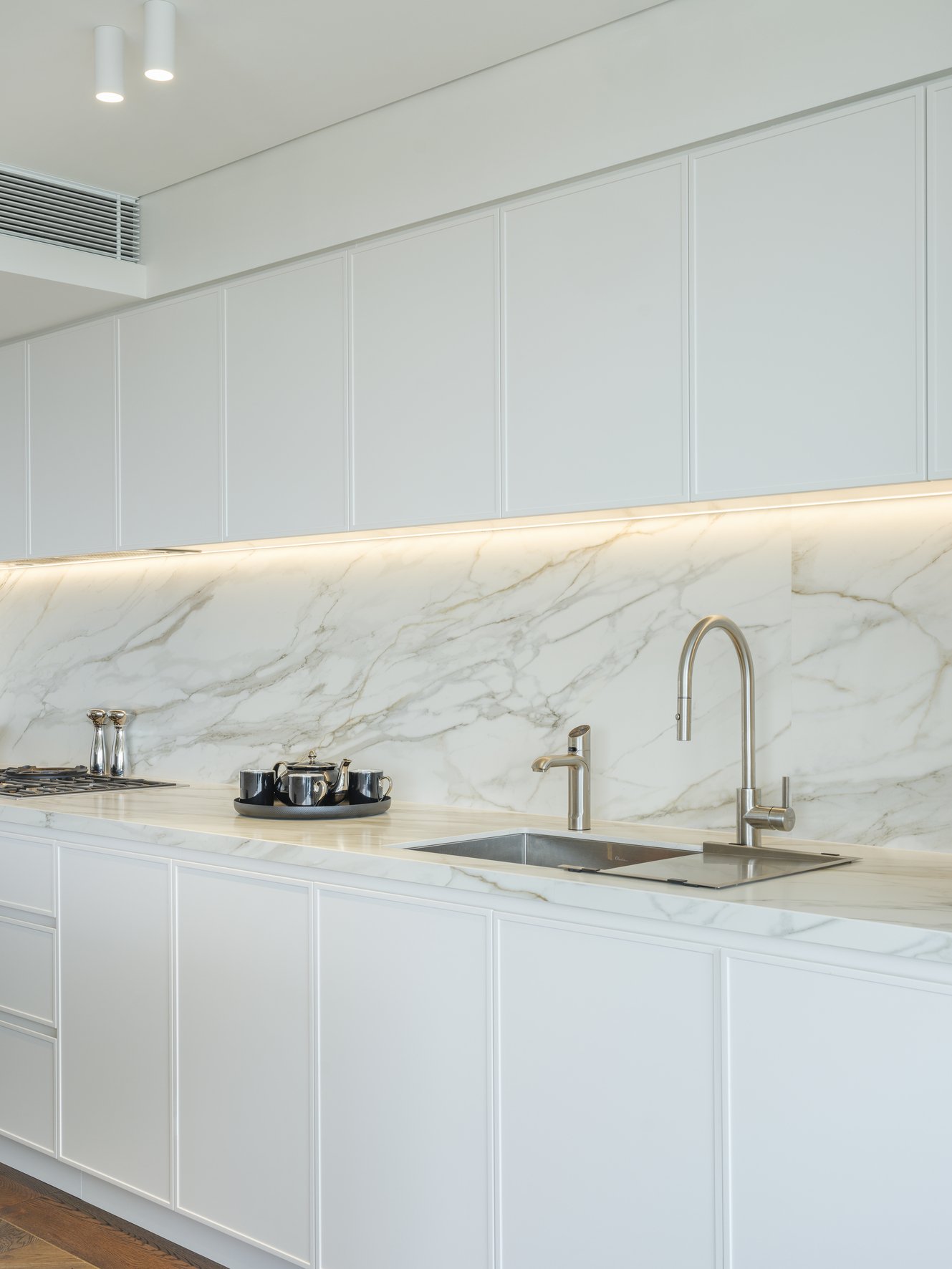 Potts Point Unit 2024 — high-end apartment renovation in Sydney featuring bespoke joinery, herringbone timber flooring with brass inlay, integrated lighting and a cohesive open-plan kitchen, living and dining space.