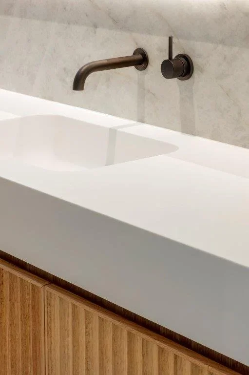 Modern bathroom sink with a wall-mounted faucet and wooden cabinet.