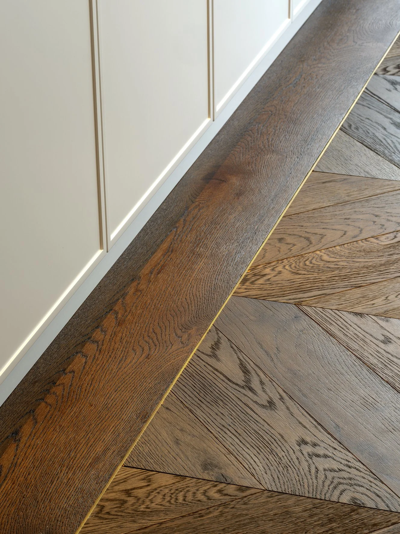 Potts Point Unit 2024 — high-end apartment renovation in Sydney featuring bespoke joinery, herringbone timber flooring with brass inlay, integrated lighting and a cohesive open-plan kitchen, living and dining space.