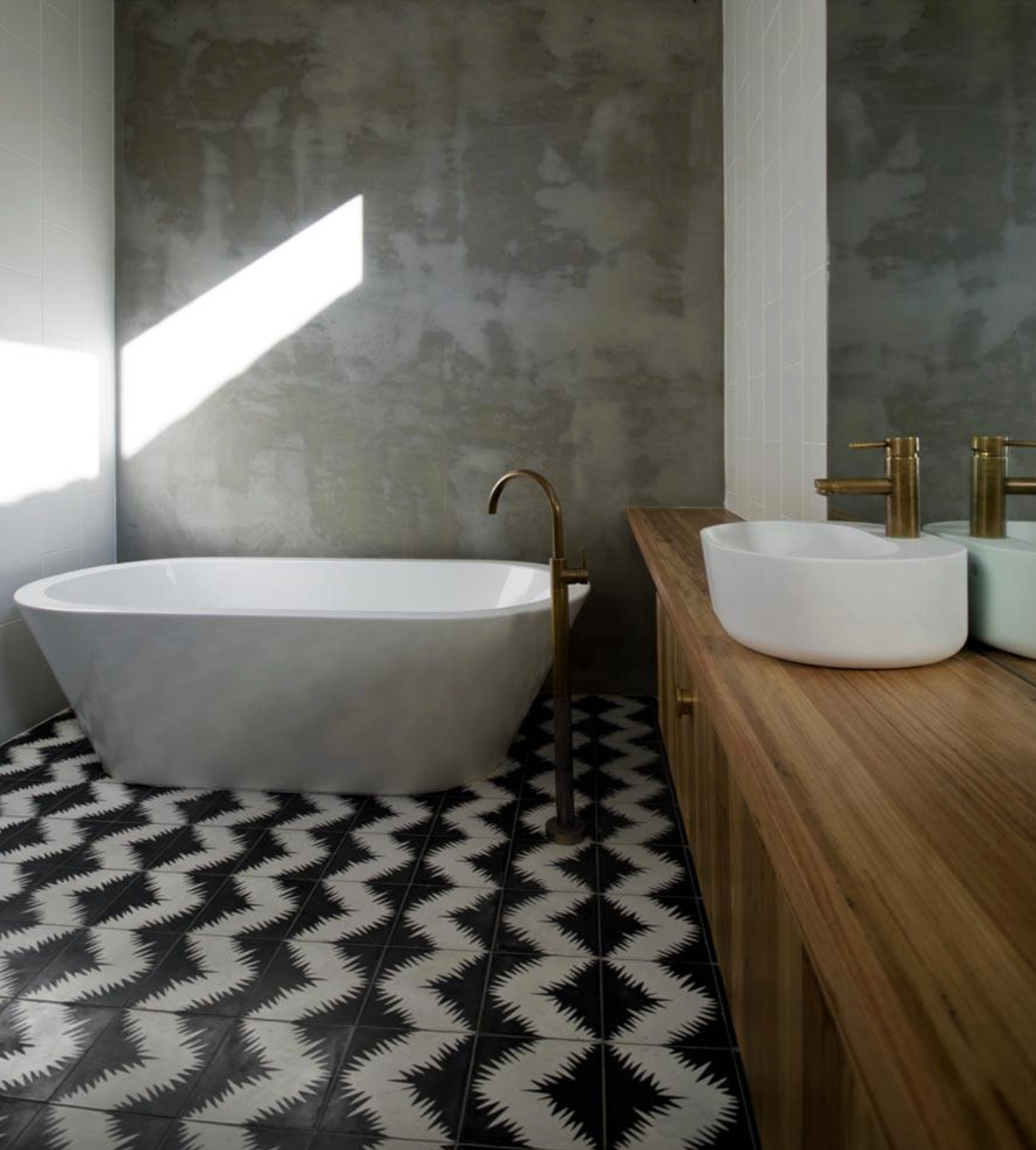 Modern bathroom with a freestanding bathtub, a wooden vanity with two vessel sinks, and black and white patterned floor tiles.