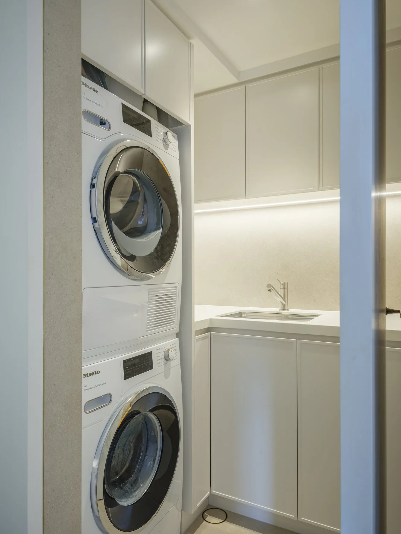 Potts Point Unit 2024 — high-end apartment renovation in Sydney featuring bespoke joinery, herringbone timber flooring with brass inlay, integrated lighting and a cohesive open-plan kitchen, living and dining space.